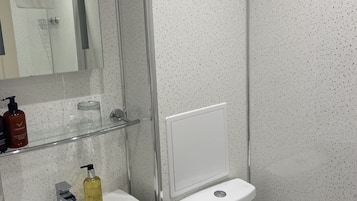 A modern bathroom with a white sink, a glass shower enclosure, and a toilet.