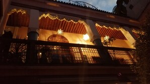 Un edificio con balcón, puertas de madera ornamentadas e iluminación decorativa.