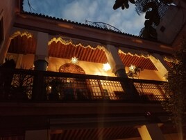 Un edificio con balcón, puertas de madera ornamentadas e iluminación decorativa.
