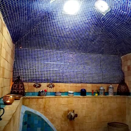 A bathroom with a tiled ceiling, a sink, and a shelf with various items.