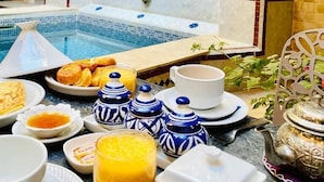 Desayuno con piscina, azulejos decorativos y diversas opciones para el desayuno.