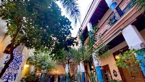 Un patio interior con piscina, zonas de estar y plantas en macetas.