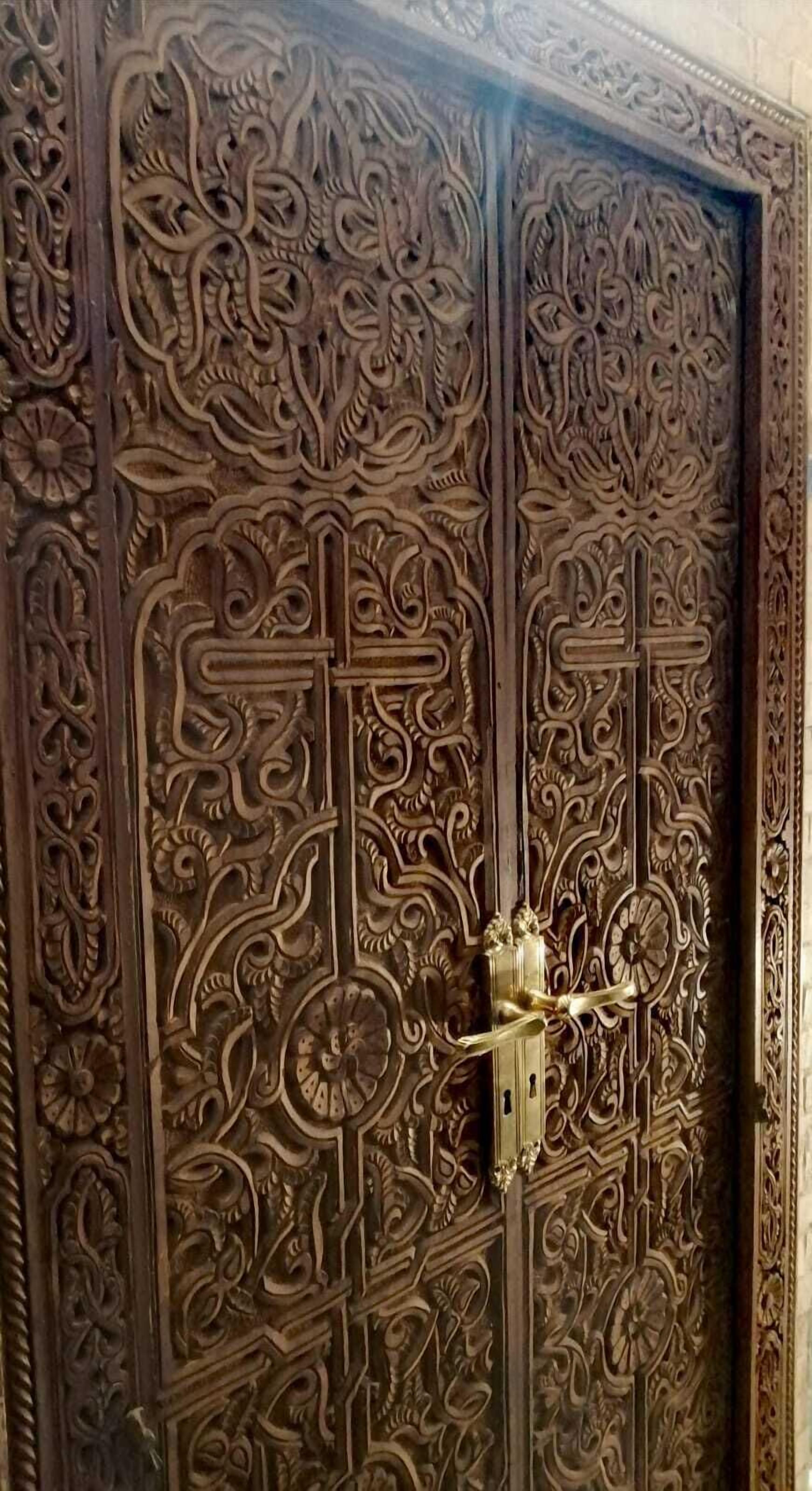 A detailed wooden door with intricate carvings and a brass handle.