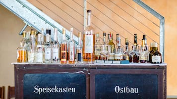 A bar area with a variety of bottles and glasses, labeled with names like "Speisekasten" and "Ostbau".