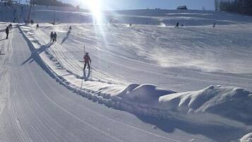 A snowy ski slope with skiers and a ski lift in the background.