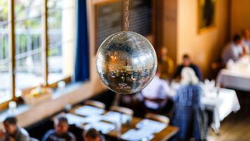 Una bola de discoteca colgando en una sala con mesas y sillas, sugiriendo un espacio para comer o socializar.