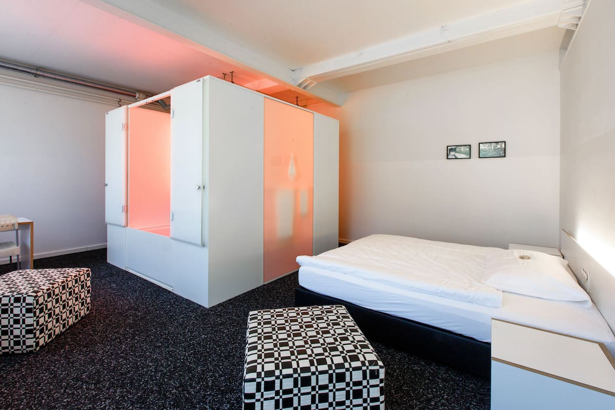 A modern hotel room with a bed, a wardrobe, and a small table.