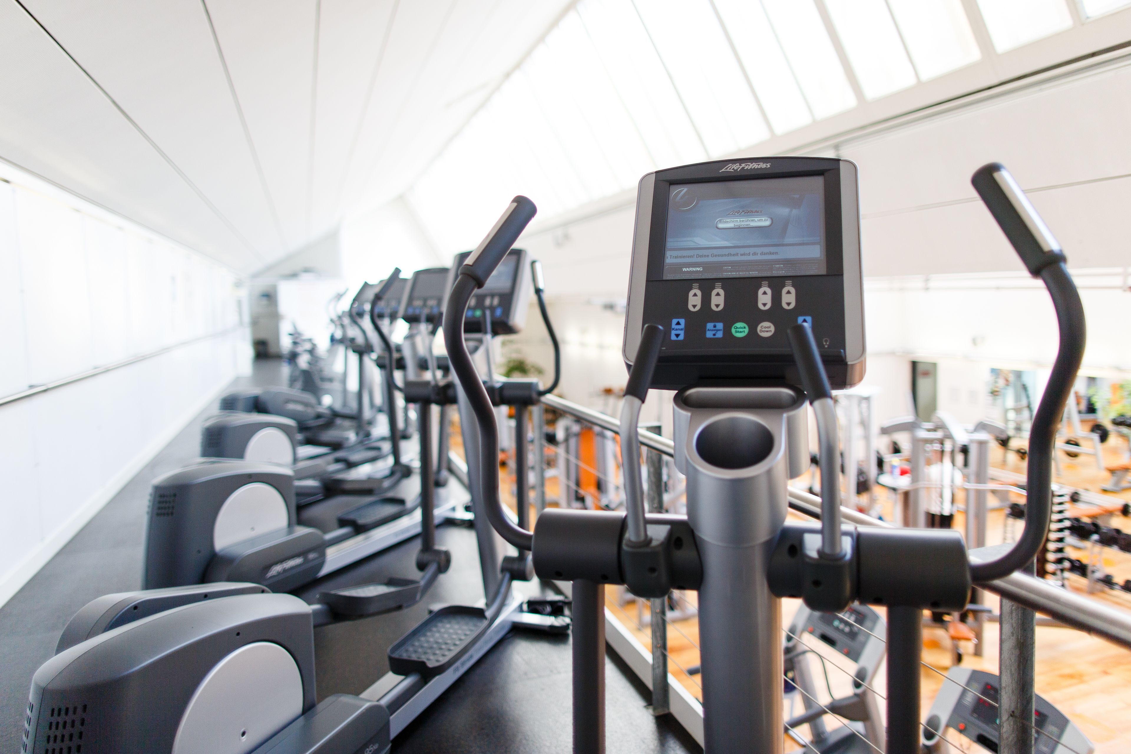 A row of stationary bikes in a gym with a digital display.