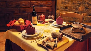 Uma mesa posta com uma garrafa de vinho, copos, pão e queijo.