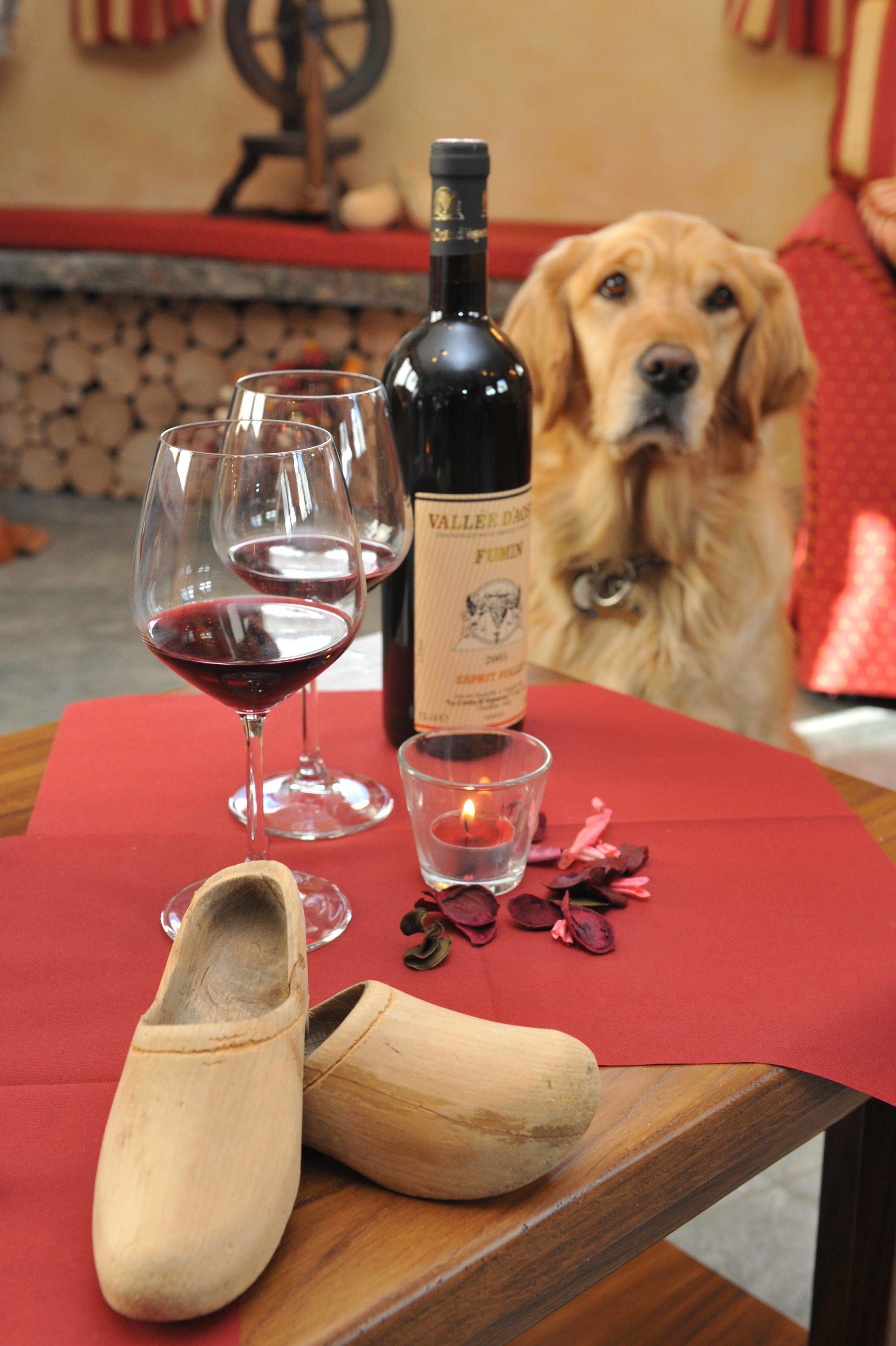 Una mesa con una botella de vino, copas, una vela y un zapato.