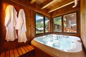 A wooden cabin with a hot tub, wooden benches, and large windows offering a view of the countryside. - Le Petit Abri (Ayas)