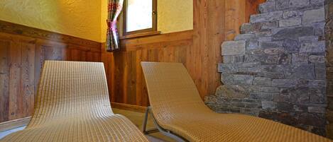 Dos sillones de mimbre en una habitación con paredes de madera y una pared de piedra.
