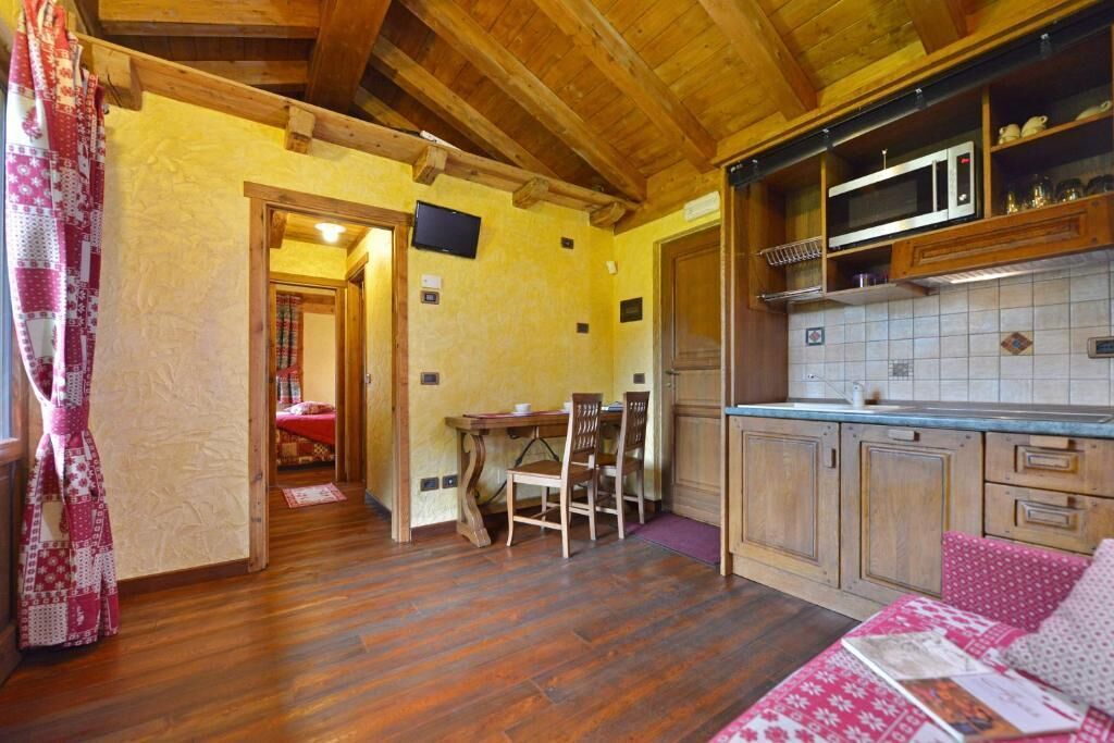 Una cocina acogedora con armarios de madera, microondas y un comedor con sillas.