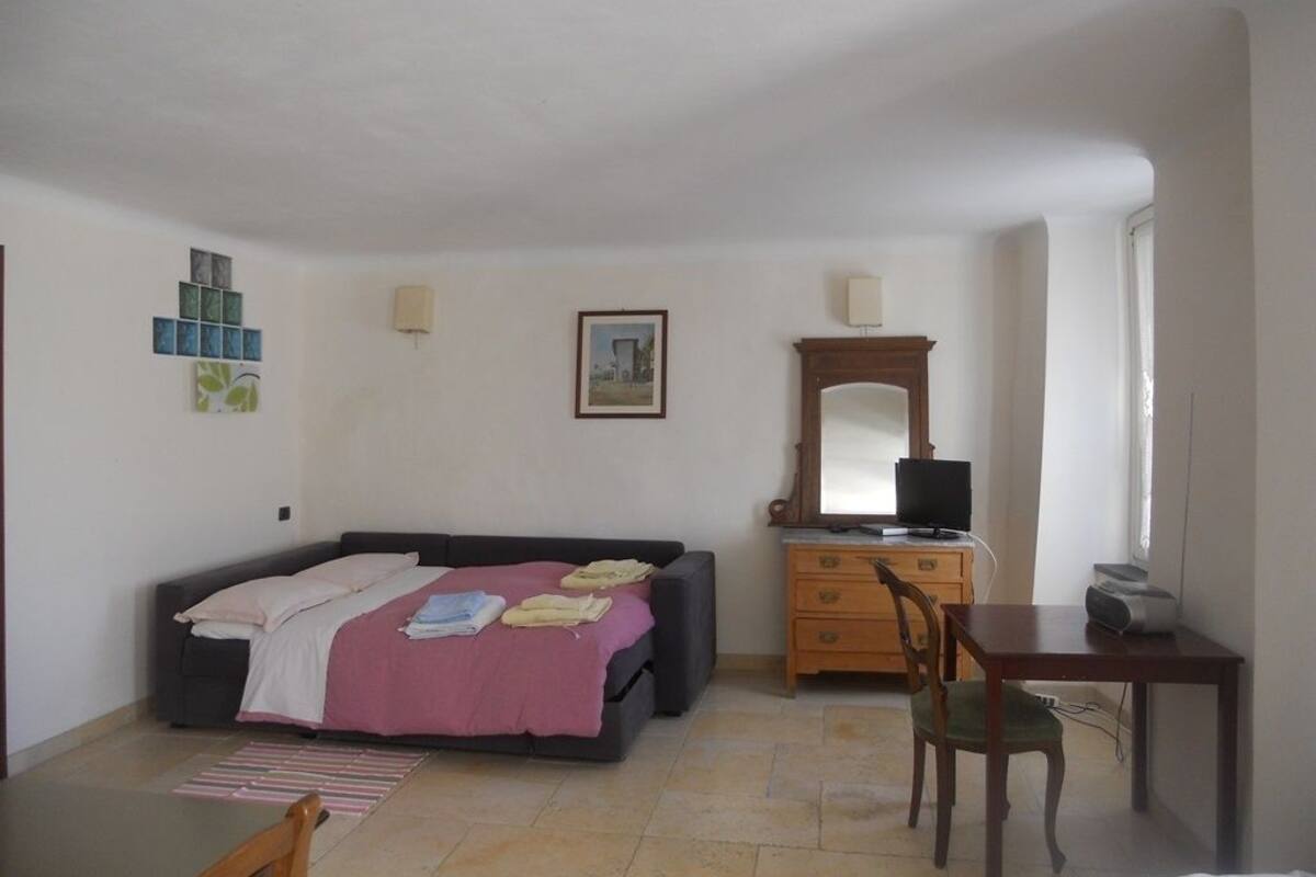A bedroom with a bed, dresser, chair, and a desk with a computer.