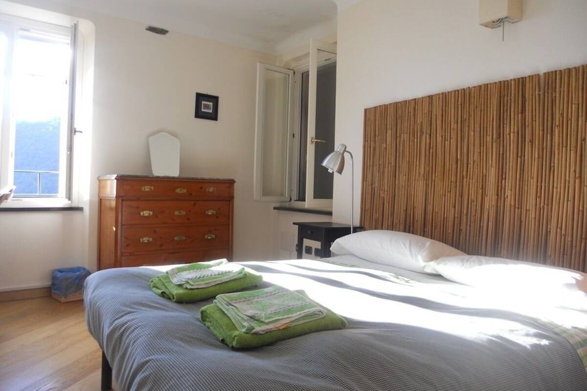 A bedroom with a bed, a wooden dresser, a mirror, and a window.
