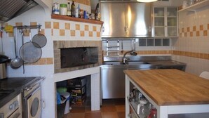 Una cocina compacta con horno integrado, microondas y lavamanos. Cuenta con una encimera de madera y un colgador para ollas.