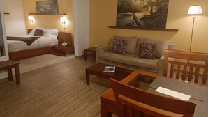Una habitación de hotel con cama, sofá, mesa de centro y un cuadro en la pared.