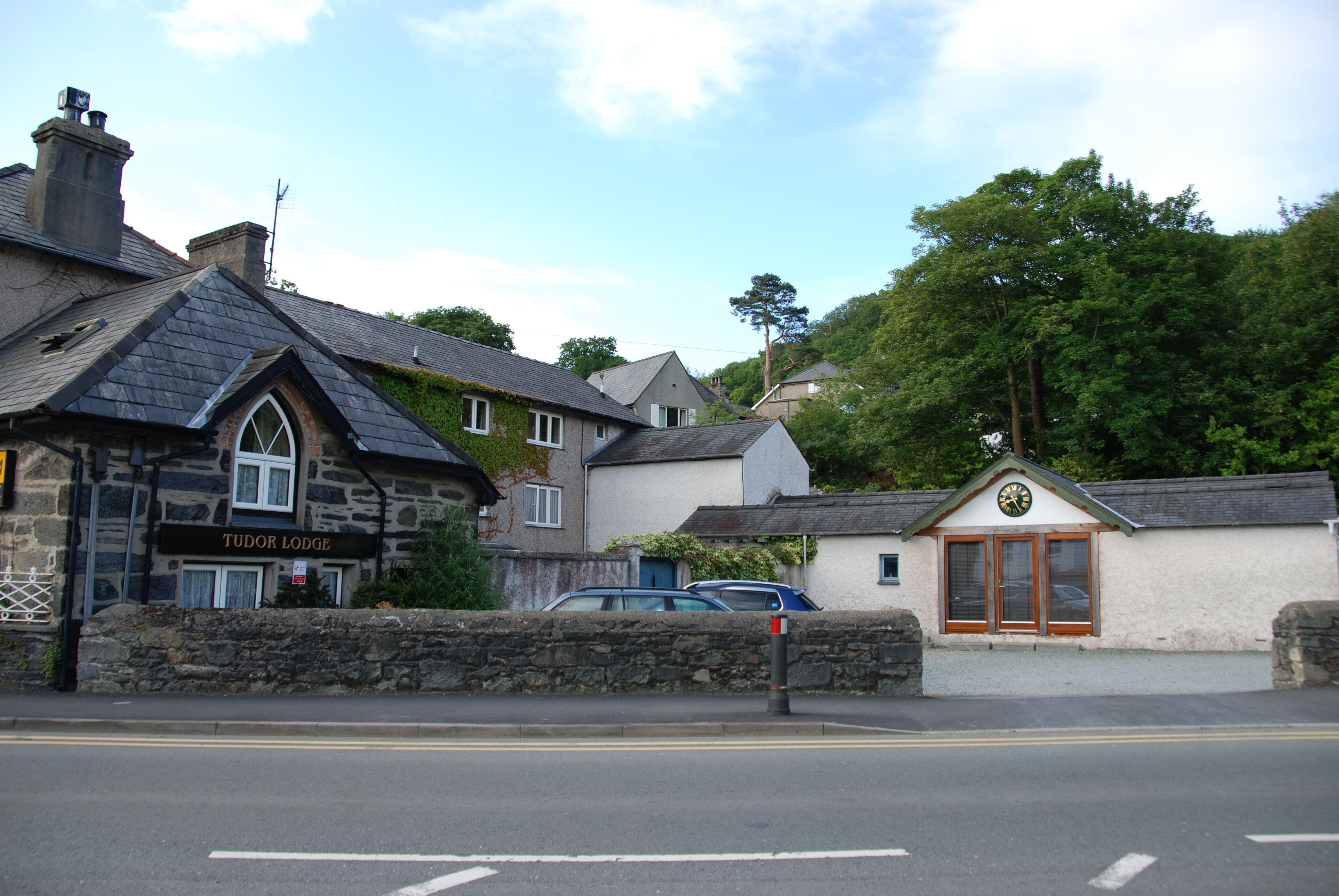 A stone building with a sign reading "Tudor Lodge" and a clock above the door.