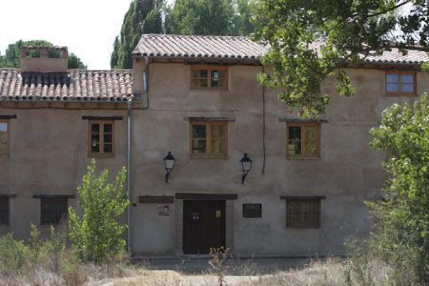 A two-story building with a tiled roof, multiple windows, and a door.