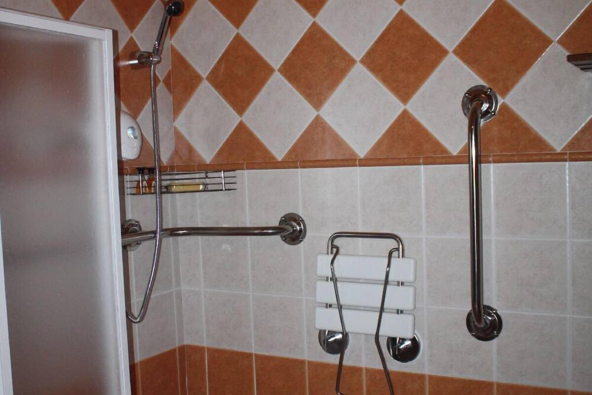 Een badkamer met douche, handgrepen en een handdoekhouder.