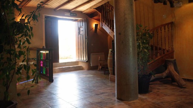 Eine geräumige Lobby mit einer Holztreppe, einer großen Säule und einer Tür zum Ausgang.