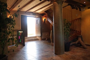 A spacious lobby with a wooden staircase, a large pillar, and a door leading outside. - El Jardín de la Huerta (Sahagun)