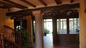 Eine geräumige Lobby mit einer Holztreppe, großen Säulen und Blick ins Freie durch große Fenster.
