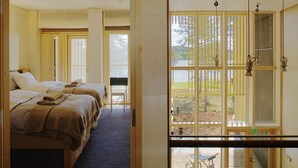 A hotel room with a bed, a chair, and a view of a lake through a window. - Anttolanhovi (Mikkeli)