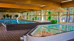 An indoor swimming pool with multiple lanes, surrounded by large windows and potted plants. - Anttolanhovi (Mikkeli)