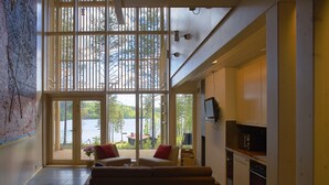 A spacious living area with a large sliding glass door leading to a deck, a sofa, and a kitchen area with cabinets and appliances. - Anttolanhovi (Mikkeli)