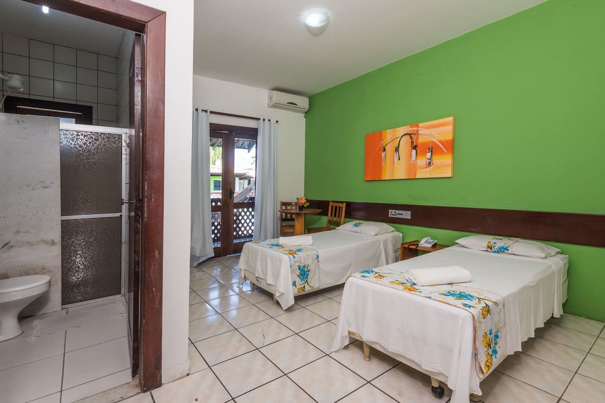 Habitació d'hotel amb dos llits, un bany i una paret verda.