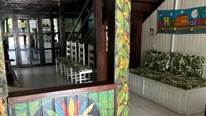 A hotel lobby with a wooden bench, a colorful mural, and a staircase leading to another area. - Hotel Vale Verde (Porto Seguro)