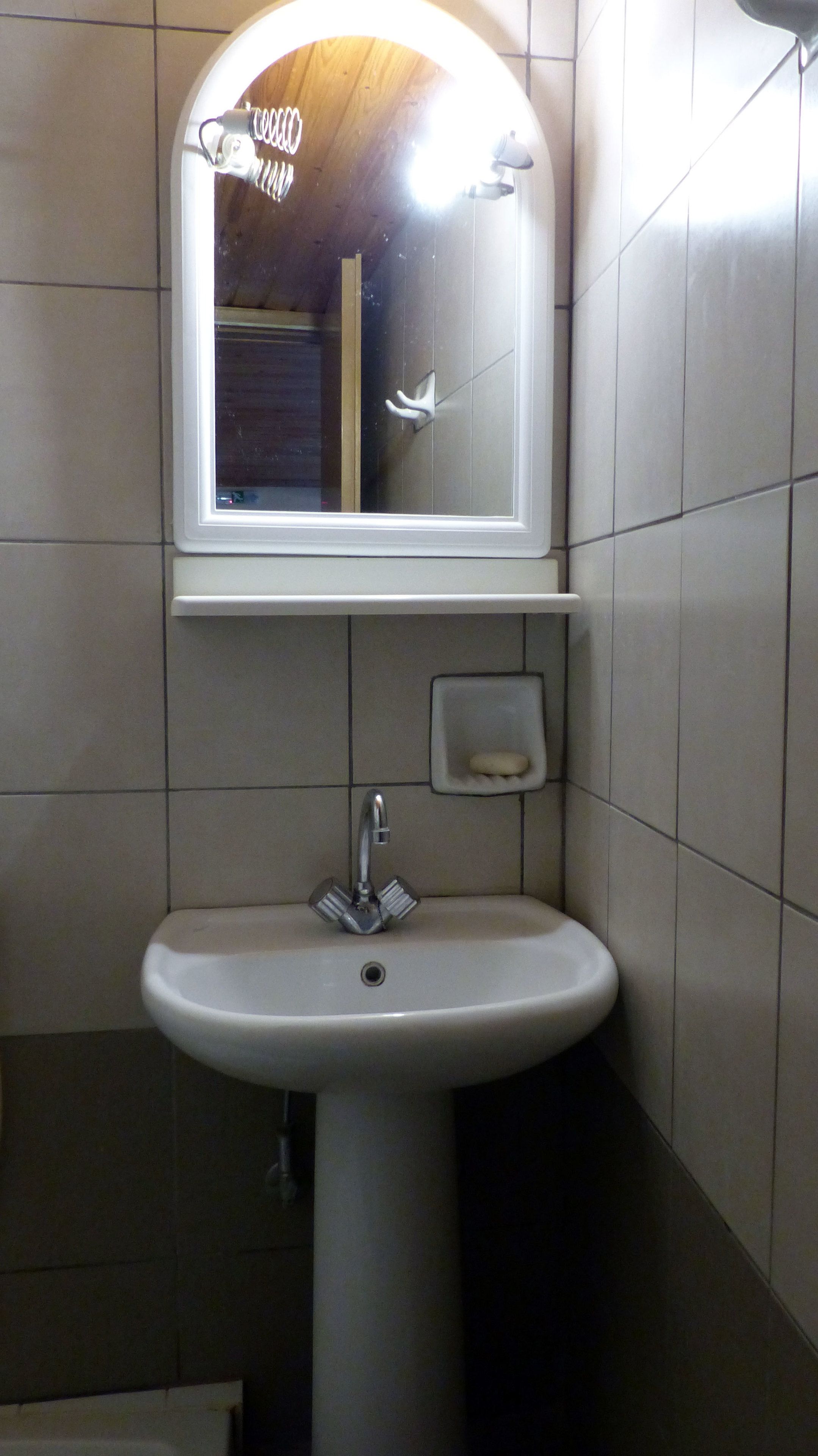 A bathroom with a white sink, a mirror, and a soap dish.