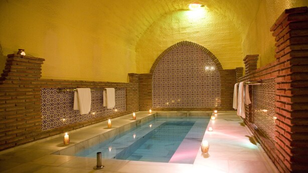 A spa area with a pool, tiled walls, and candles.