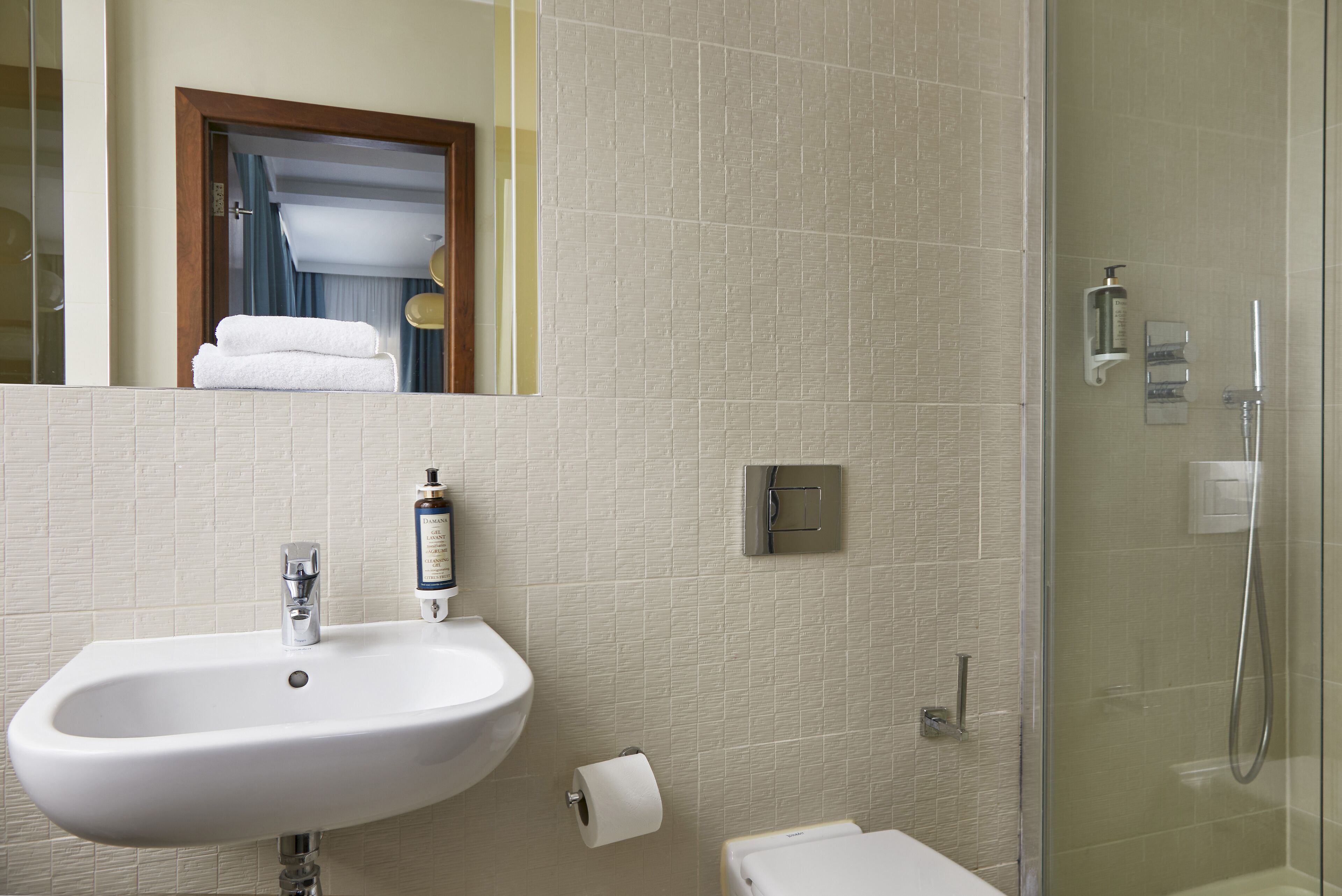 A bathroom with a sink, toilet, and a glass-enclosed shower area.