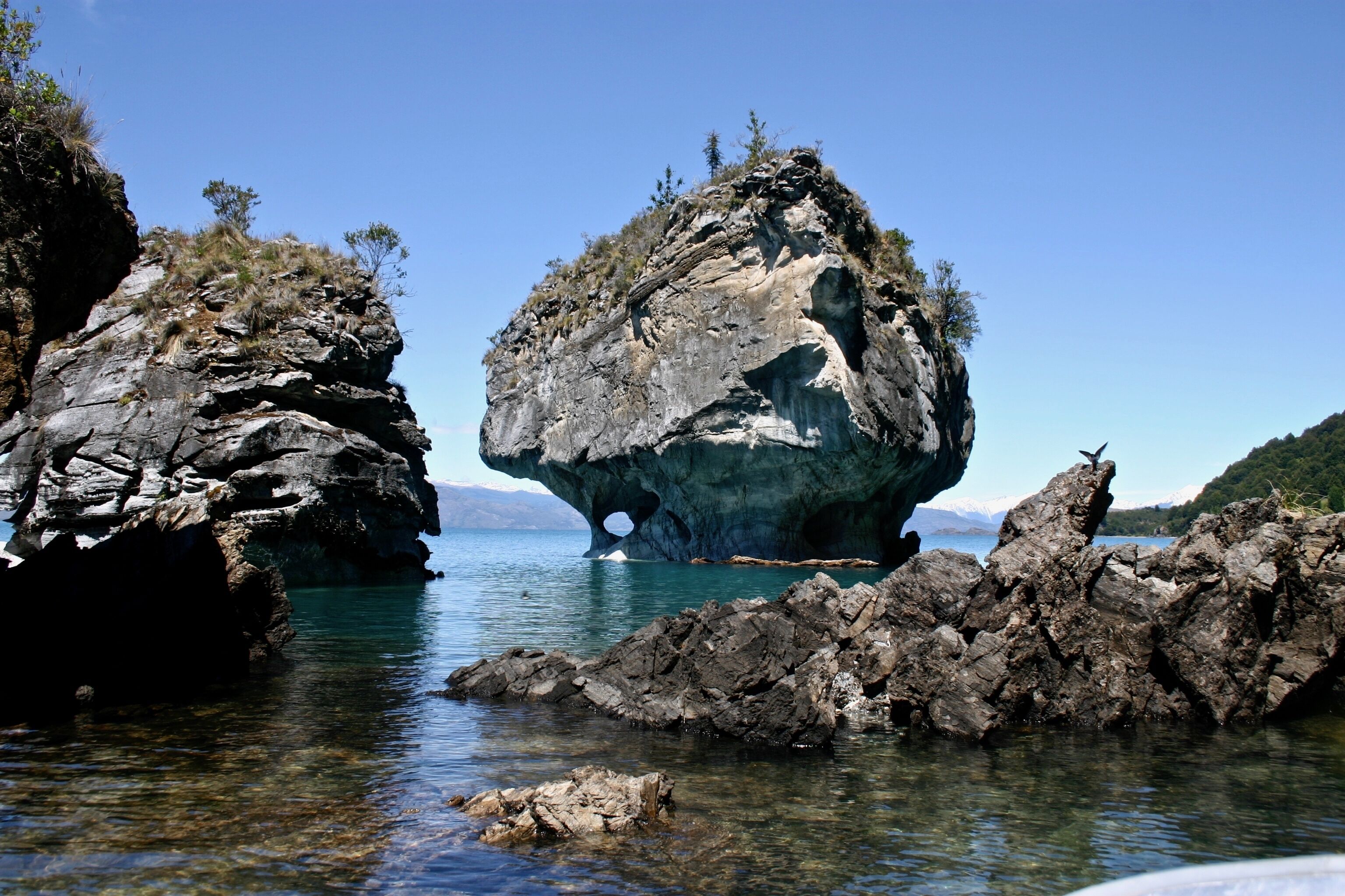 A natural rock formation with clear water in front.