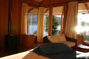 A cozy room with a bed, a sofa, a small table, and a window with curtains. - El Mirador de Guadal (Puerto Guadal)