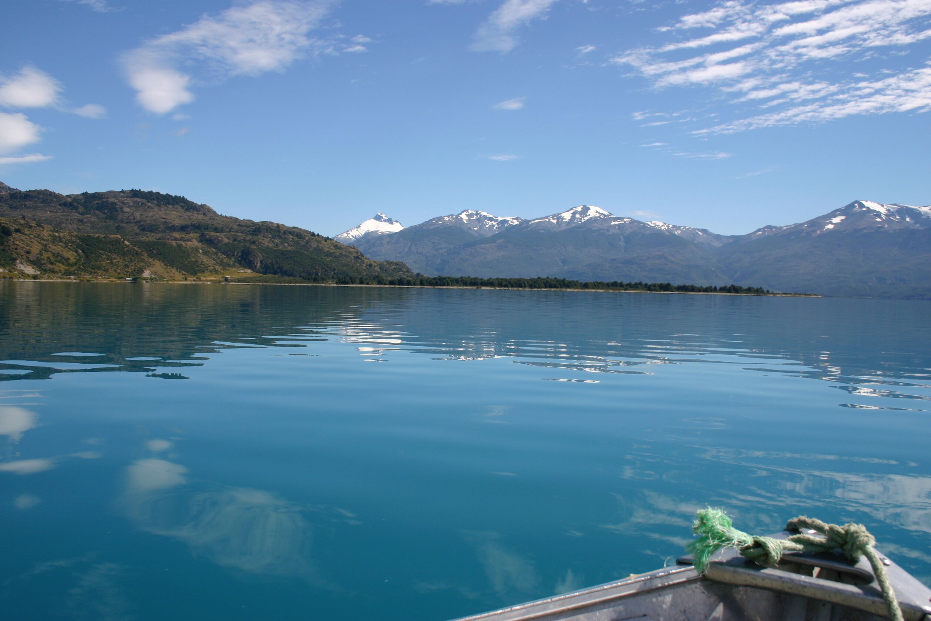 Un llac tranquil amb muntanyes al fons i una barca al primer pla.