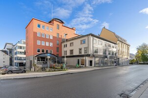 Un hotel con fachada moderna, entrada visible y cielo despejado.