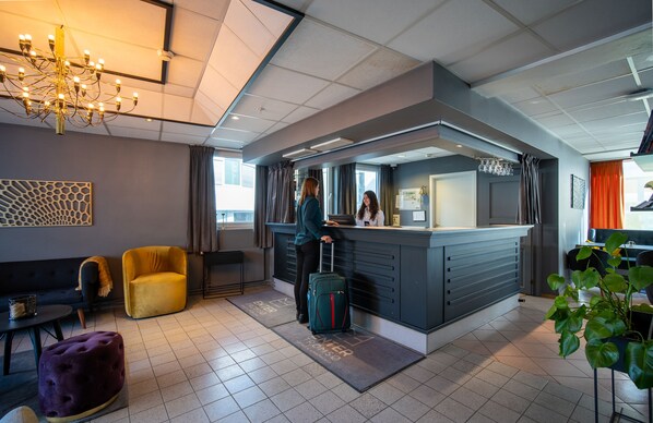 A modern hotel lobby with a reception desk, seating area, and a chandelier. - First Hotel Amalie (Tromsø)