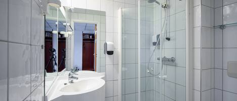 A modern bathroom with a glass-enclosed shower, a white sink, and a large mirror.