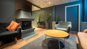 A modern living room with a fireplace, a sofa, a chair, and a coffee table. - First Hotel Amalie (Tromsø)