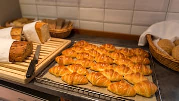 A tray of freshly baked croissants and a loaf of bread on a kitchen counter.