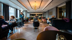 A modern dining area with tables and chairs, a chandelier, and large windows. - First Hotel Amalie (Tromsø)