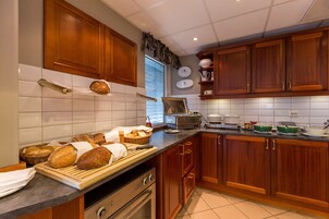 Una cocina con armarios de madera, un horno de acero inoxidable y una encimera con pan y utensilios de cocina.