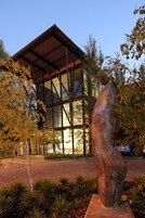 A modern building with a glass facade and a metal sculpture in front.