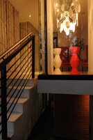 A modern staircase with a black railing, leading to a second-floor landing with a unique chandelier and contemporary decor.