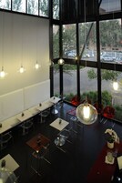 A modern interior with high ceilings, large windows, and a mix of seating arrangements including tables and chairs.