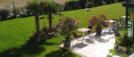 A patio area with a table and chairs, surrounded by potted plants and flowers.