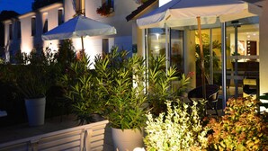 Ein gut beleuchteter Außenbereich mit Topfpflanzen und Sonnenschirmen, der eine Terrasse oder einen Garten andeutet.